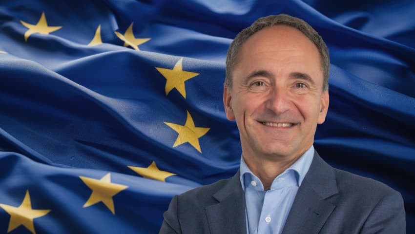 Jim Hagemann Snabe, smiling and wearing a dark blazer over a light blue shirt, against a backdrop of the European Union flag.